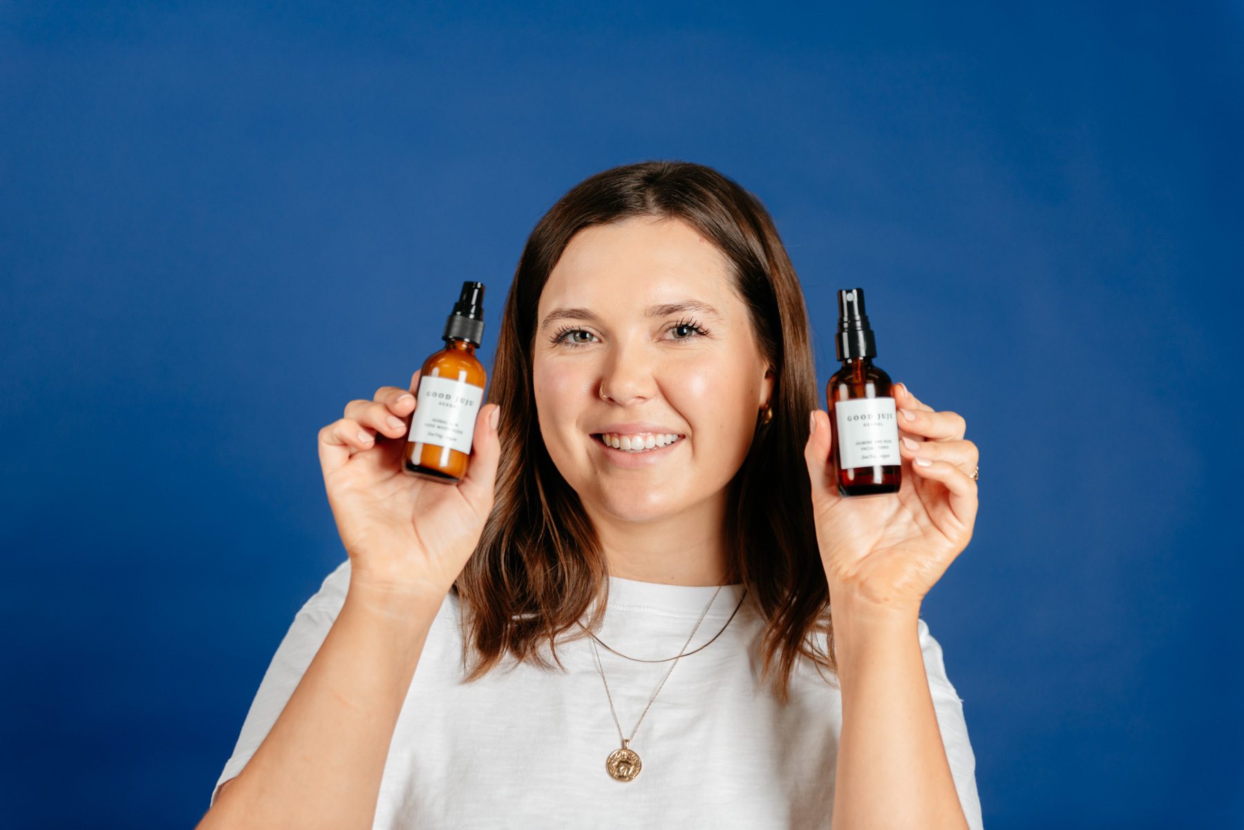 Judith Jones holds up two of her company's products with the 'Good Juju' label in plain view as she smiles for the camera.