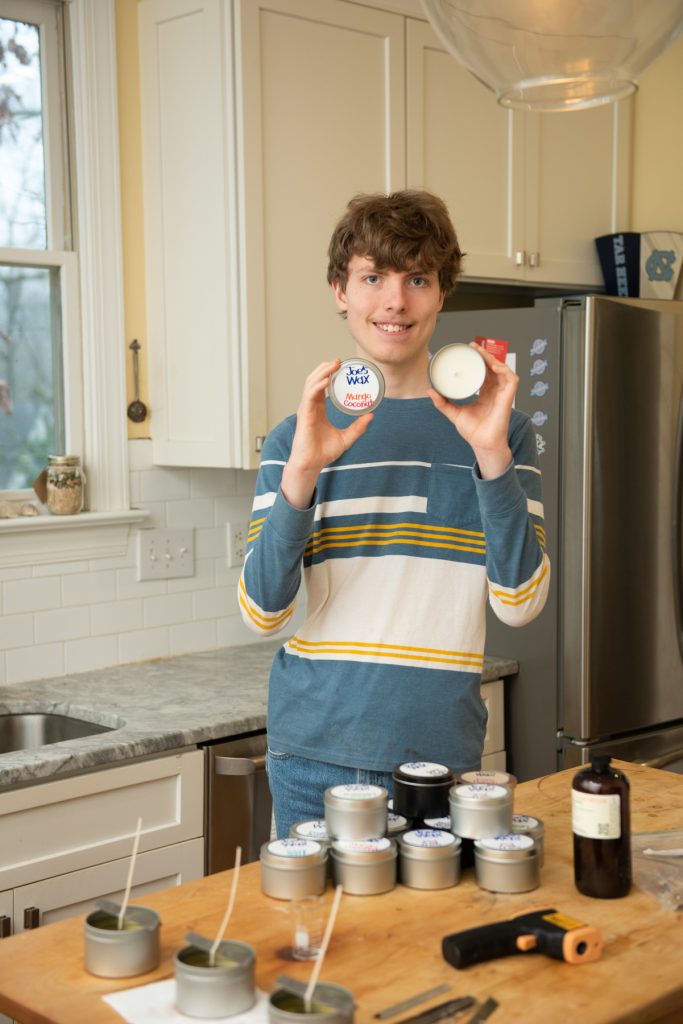 Joe Branan of Joe’s Wax holding a mango-coconut candle in his family’s kitchen.