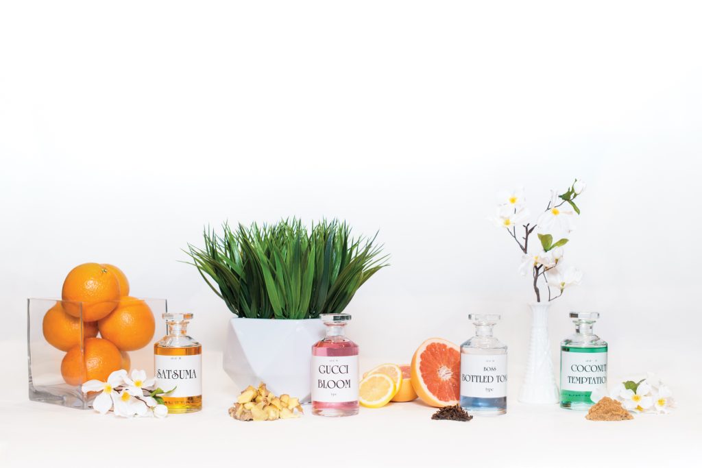 Perfume bottles from The Fragrance Shop arranged with citrus, flowers and ingredients.