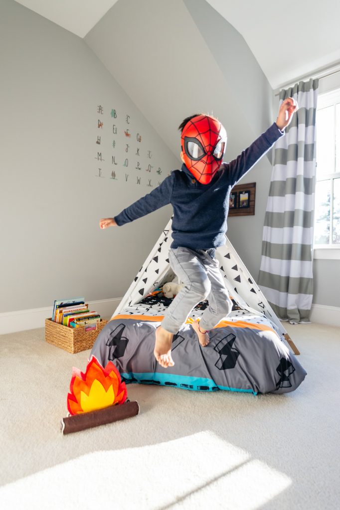 Child wearing a Spider-Man mask jumping in the air in a room at the Skurky family’s home.