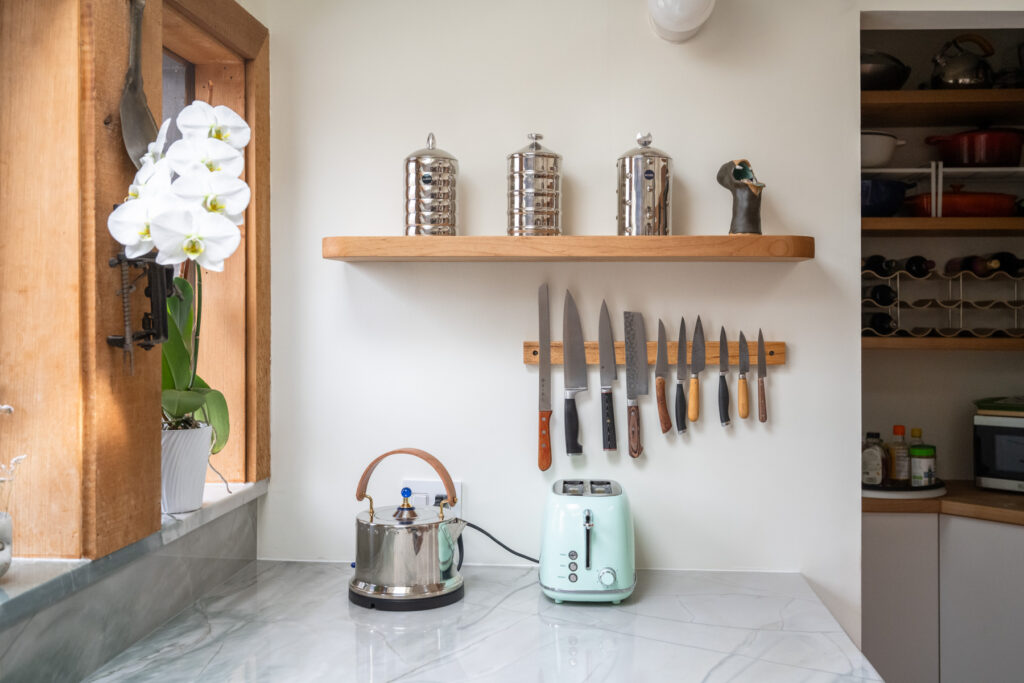 Knives are and containers are on display in the kitchen corner, with a pantry tucked away behind the wall.