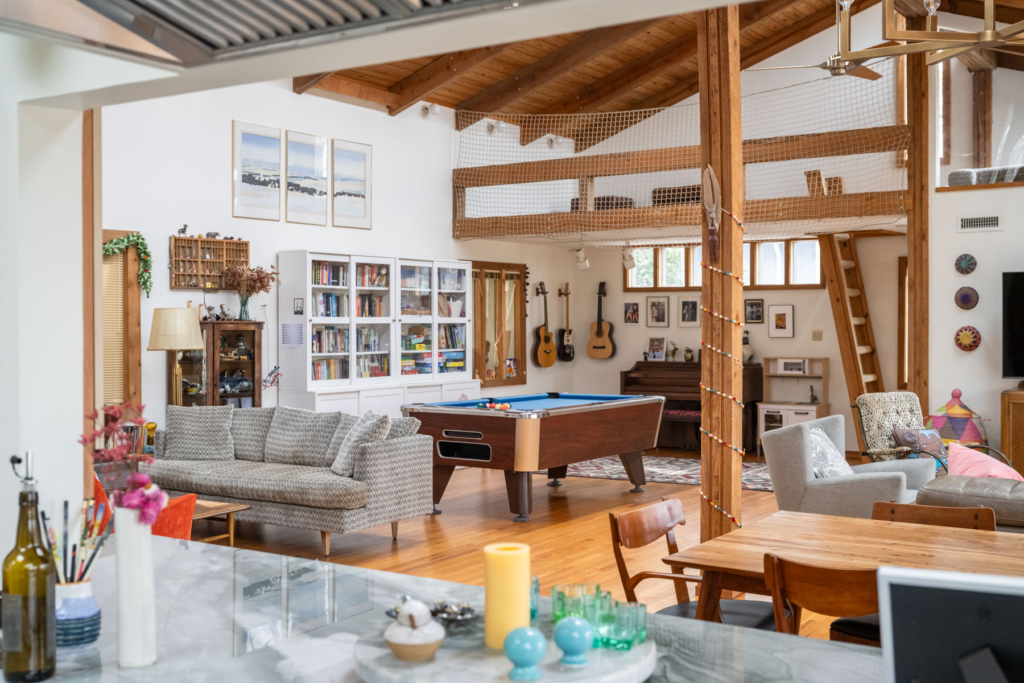 A vibrant living area with a pool table, guitars, bookshelves and a loft.
