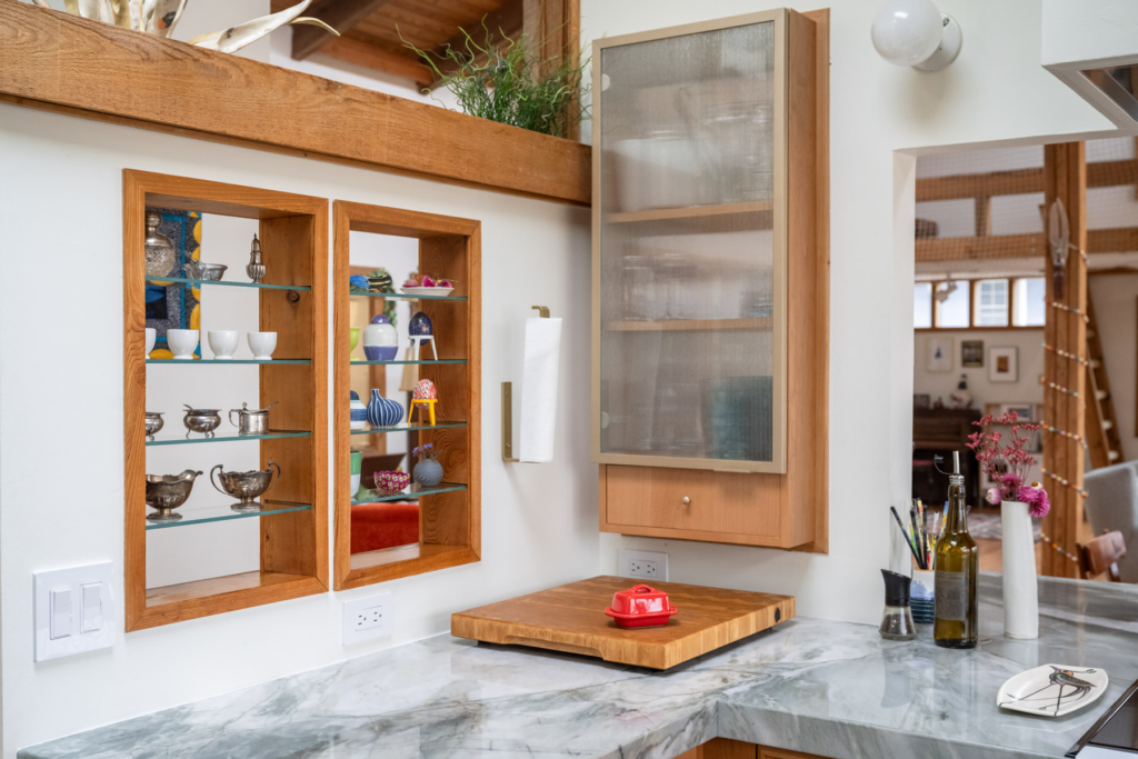 Ceramics and glass pieces on display in a bright kitchen corner.
