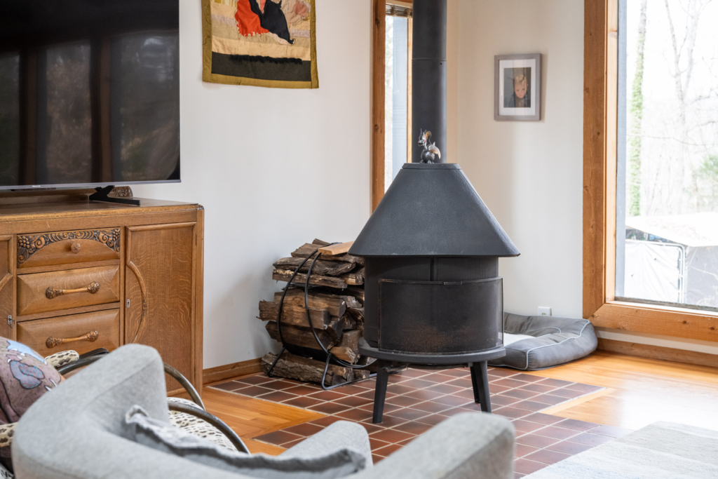 A freestanding wood-burning fireplace sits on tiles in a living room.