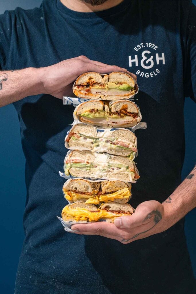 H&H Bagels employee shows off different bagel sandwich verities.